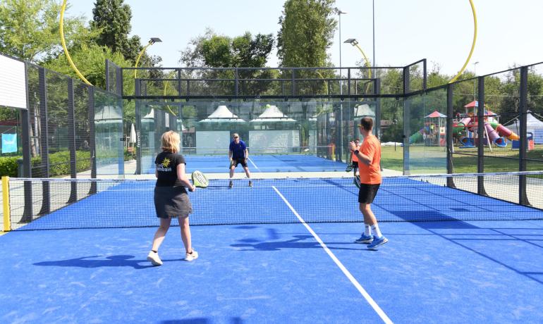 Padelspelers op een buitenbaan met blauw kunstgras.