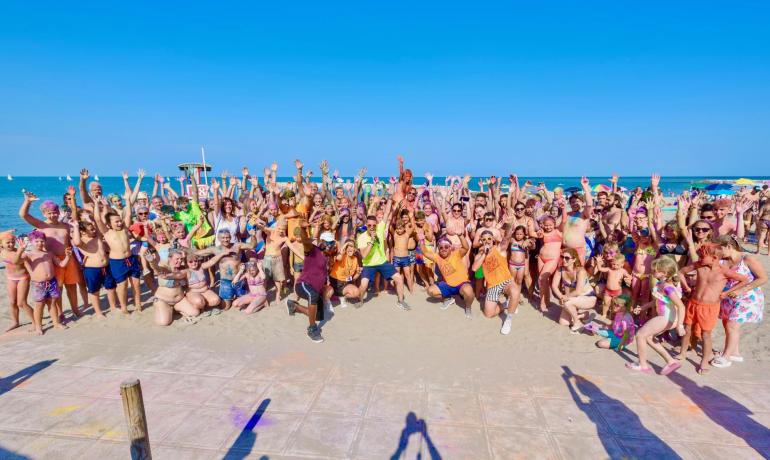 Groep mensen op het strand die enthousiast en met levendige kleuren vieren.