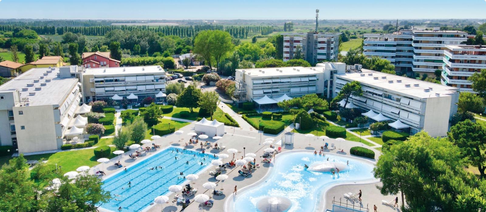 Complesso con piscine, giardini verdi e edifici moderni, atmosfera di relax e vacanza.