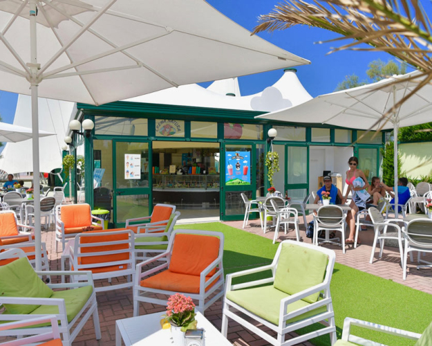 Bar all'aperto con sedie colorate e ombrelloni, atmosfera estiva e rilassante.